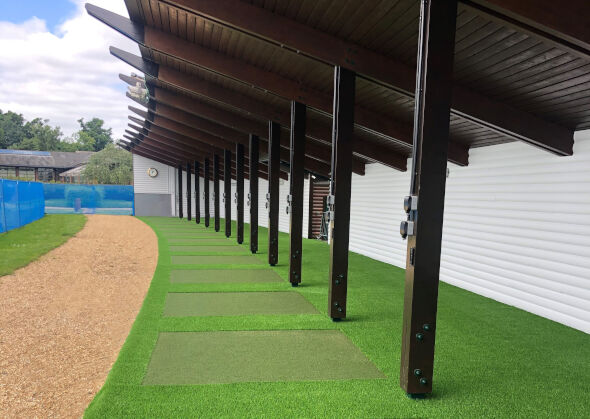 Greenwich Covered outdoor tee line with light green synthetic grass boxes inside a dark green synthetic grass strip